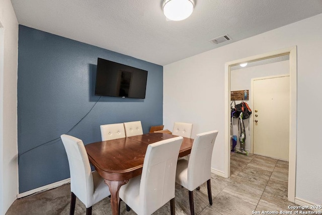 dining space with visible vents, a textured ceiling, and baseboards