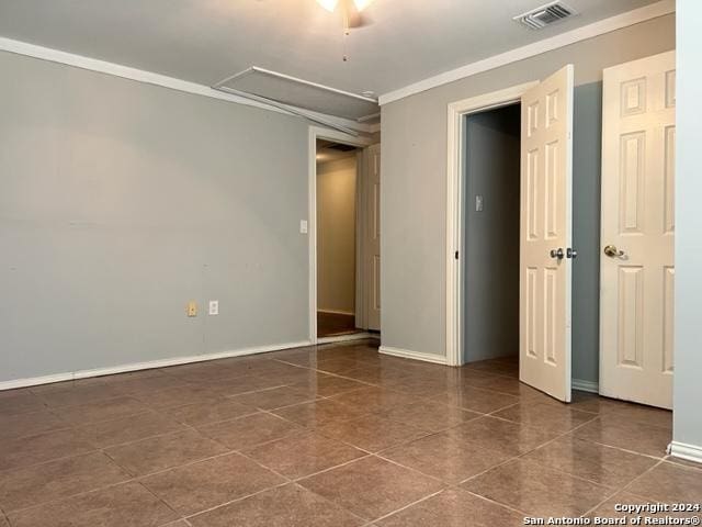 spare room with attic access, visible vents, baseboards, and ornamental molding