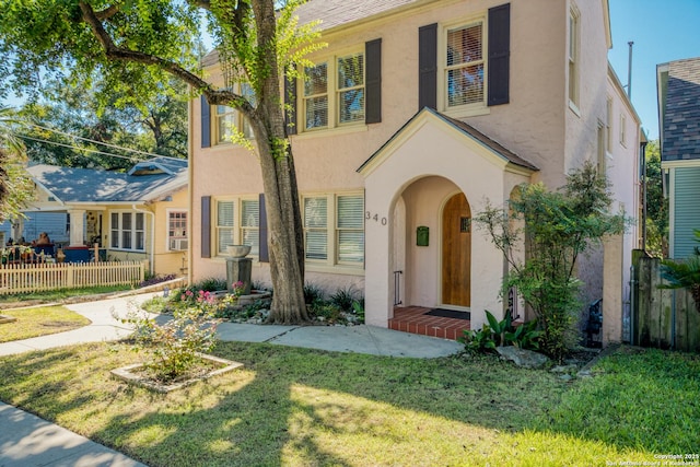 view of front facade with a front yard, fence, and stucco siding