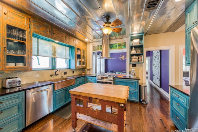 kitchen with glass insert cabinets, appliances with stainless steel finishes, dark wood-style flooring, a sink, and backsplash