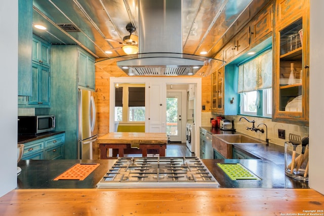 kitchen with washer and clothes dryer, tasteful backsplash, appliances with stainless steel finishes, a sink, and island range hood