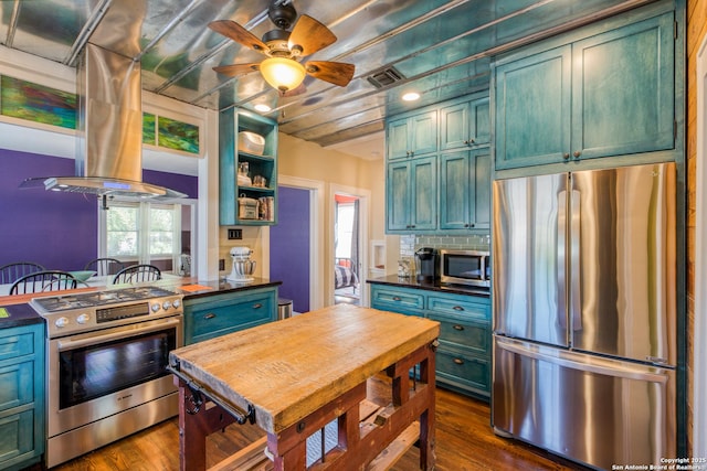 kitchen with stainless steel appliances, dark countertops, visible vents, and island exhaust hood