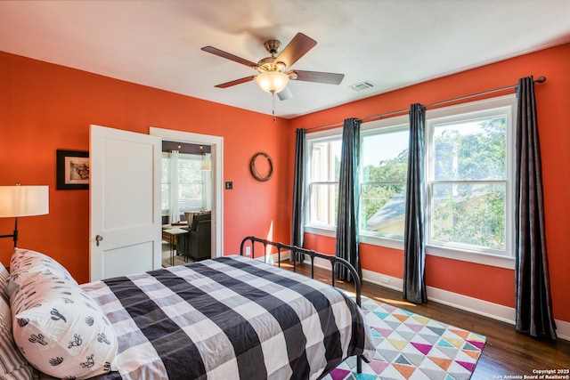 bedroom with dark wood-style floors, ceiling fan, visible vents, and baseboards