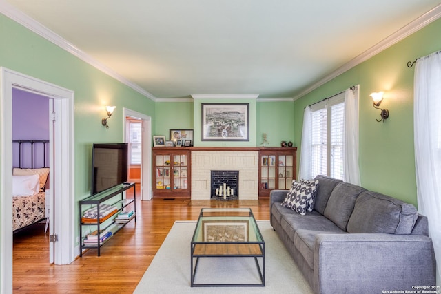 living area with ornamental molding, a fireplace, and wood finished floors