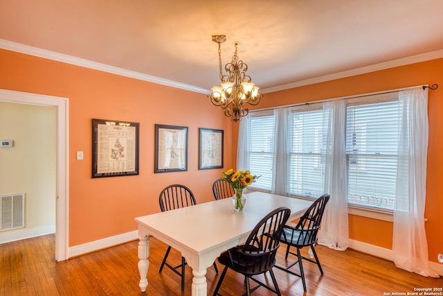 dining area featuring ornamental molding, visible vents, and light wood finished floors