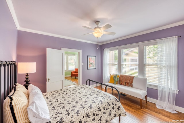 bedroom featuring multiple windows, crown molding, light wood-style flooring, and baseboards