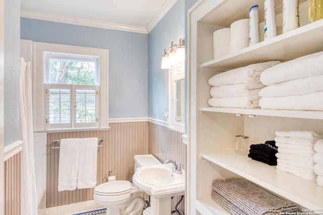 bathroom featuring wainscoting, crown molding, a sink, and toilet