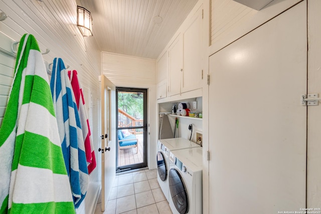 laundry area with cabinet space, light tile patterned flooring, and washing machine and clothes dryer