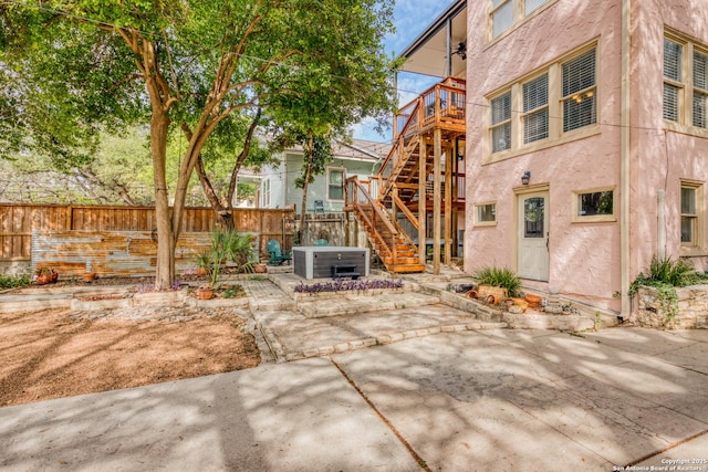 back of property featuring stairs, a patio, stucco siding, and a hot tub