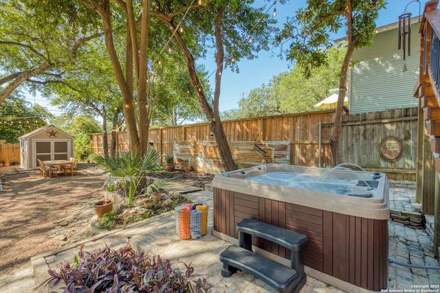 view of patio / terrace featuring an outbuilding, a fenced backyard, a hot tub, and a storage shed