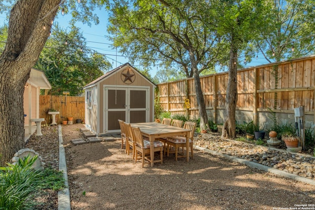 view of patio / terrace with outdoor dining space, a fenced backyard, an outdoor structure, and a shed