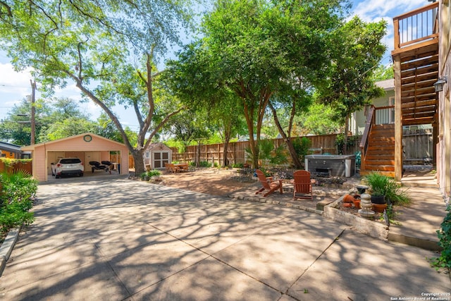 view of patio / terrace featuring stairway, an outdoor structure, fence, and a hot tub