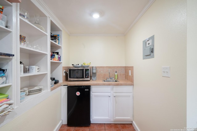 kitchen featuring refrigerator, a sink, electric panel, stainless steel microwave, and crown molding