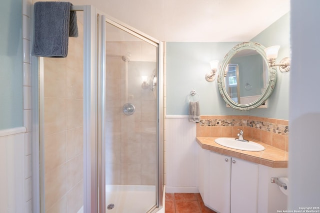 bathroom featuring a wainscoted wall, a stall shower, vanity, and tile patterned floors