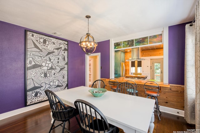 dining space featuring dark wood-type flooring, visible vents, a notable chandelier, and baseboards