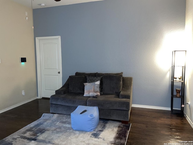 living room with a ceiling fan, baseboards, and wood finished floors