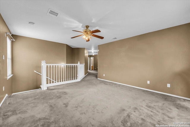 carpeted spare room featuring a ceiling fan, visible vents, and baseboards