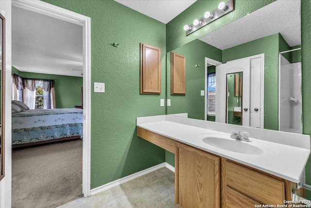 full bathroom featuring a textured wall, baseboards, connected bathroom, and vanity