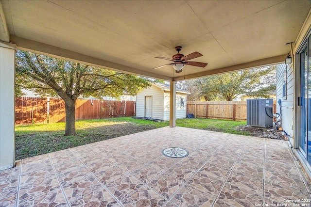 view of patio / terrace with a ceiling fan, a fenced backyard, an outbuilding, a storage unit, and central AC