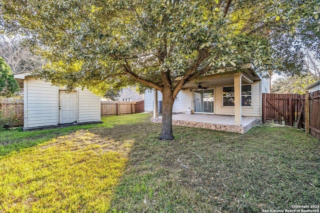 view of yard with ceiling fan, a patio, an outbuilding, a fenced backyard, and a storage shed