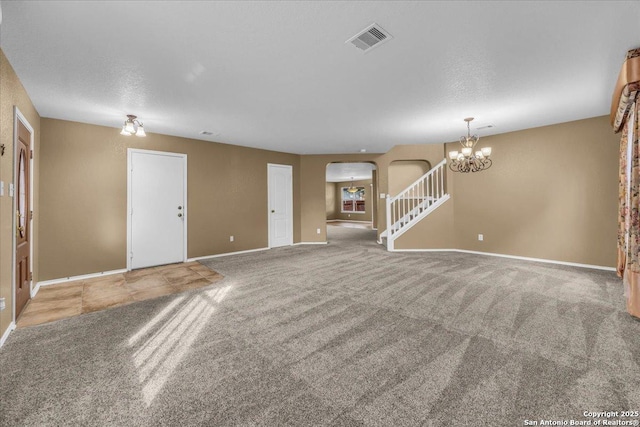 unfurnished living room with carpet floors, arched walkways, a notable chandelier, visible vents, and stairway