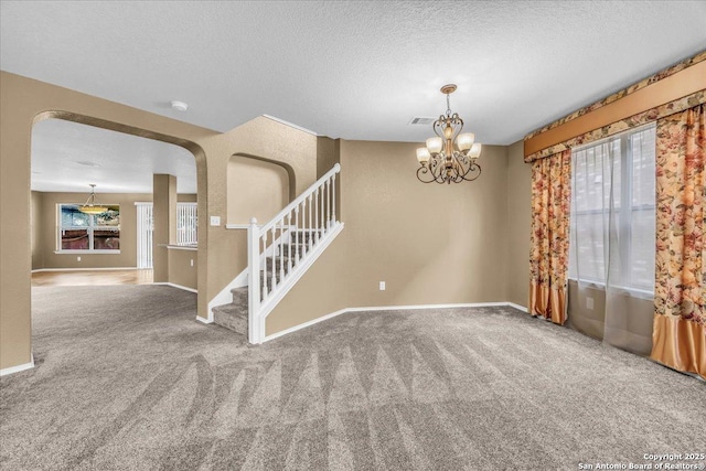 unfurnished room featuring carpet flooring, stairway, and a textured ceiling