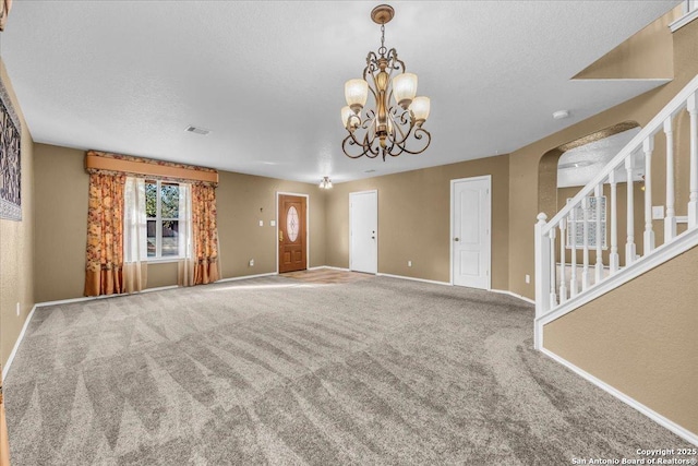 unfurnished living room featuring visible vents, arched walkways, stairs, a textured ceiling, and carpet flooring