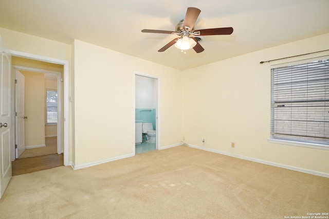 unfurnished bedroom featuring light colored carpet, ceiling fan, baseboards, and ensuite bathroom