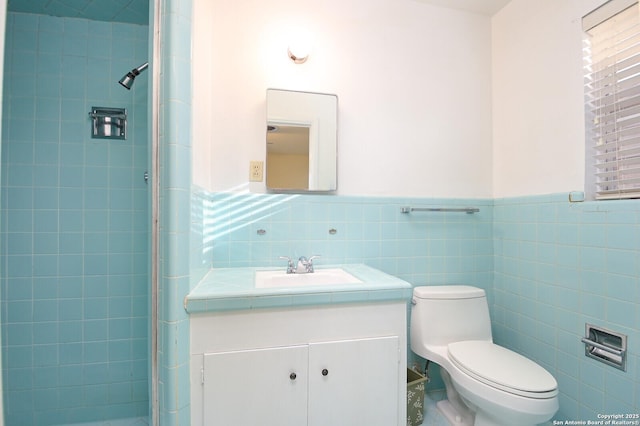 bathroom featuring a wainscoted wall, tile walls, toilet, a tile shower, and vanity