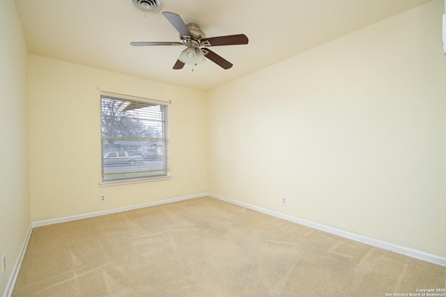 spare room featuring light colored carpet, visible vents, ceiling fan, and baseboards