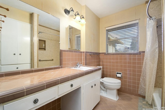 full bathroom with tile patterned flooring, toilet, a wainscoted wall, tile walls, and a shower with curtain