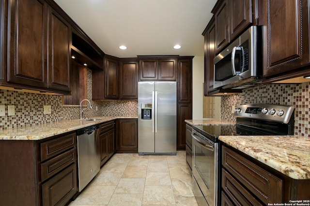 kitchen featuring stainless steel appliances, dark brown cabinets, backsplash, and a sink