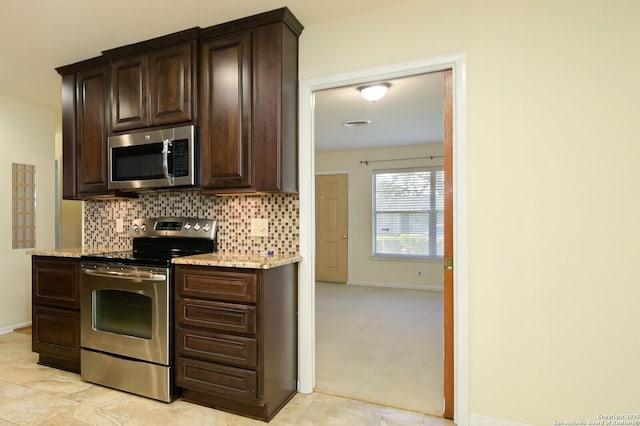 kitchen featuring dark brown cabinetry, tasteful backsplash, baseboards, appliances with stainless steel finishes, and light stone counters