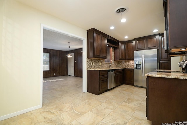 kitchen with dark brown cabinetry, stainless steel appliances, visible vents, light stone countertops, and tasteful backsplash