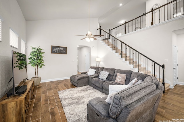 living room featuring high vaulted ceiling, baseboards, arched walkways, and dark wood-style flooring