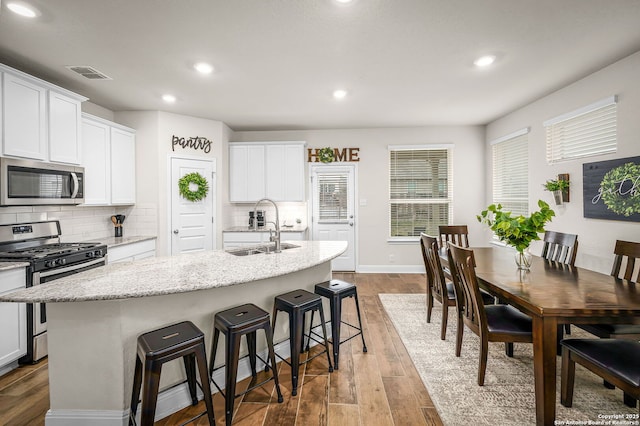 kitchen with visible vents, an island with sink, dark wood-style floors, appliances with stainless steel finishes, and a sink