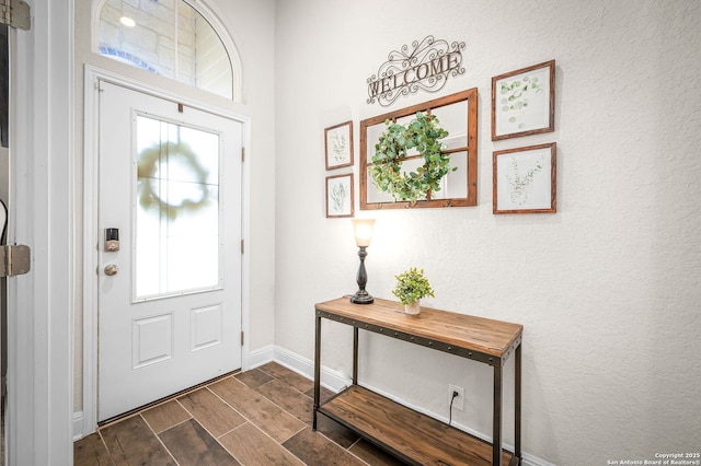 entryway featuring a textured wall, baseboards, and wood finish floors