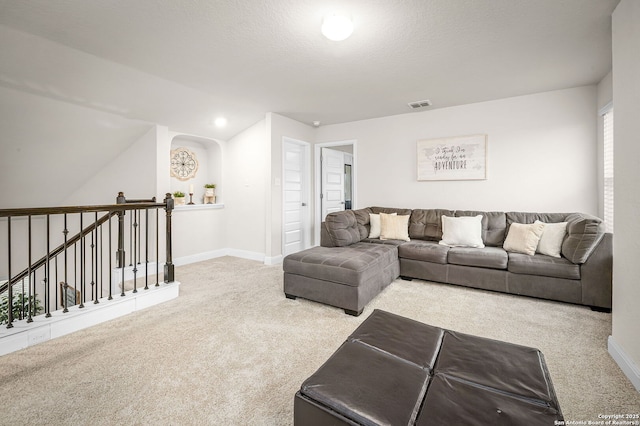 carpeted living area featuring baseboards, visible vents, and a textured ceiling