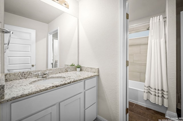 full bath featuring shower / bath combination with curtain, wood tiled floor, a textured wall, and vanity