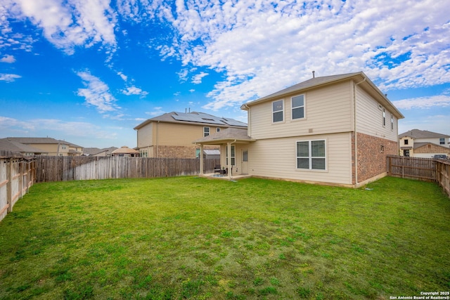 back of house featuring a yard, brick siding, a patio, and a fenced backyard