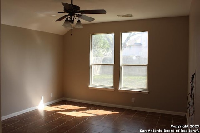 unfurnished room with baseboards, visible vents, a ceiling fan, vaulted ceiling, and dark tile patterned floors