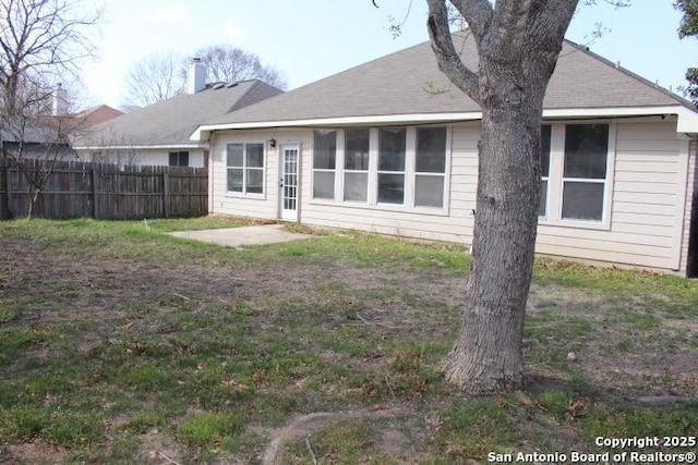 rear view of property featuring a patio, a shingled roof, and fence