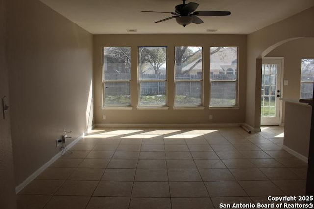 tiled spare room with a ceiling fan, arched walkways, and baseboards