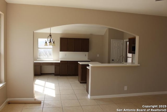 kitchen featuring light tile patterned floors, baseboards, decorative light fixtures, light countertops, and dark brown cabinets