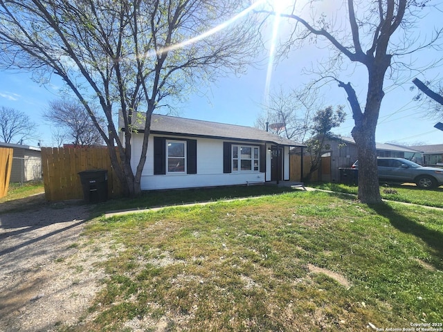 view of front of property featuring driveway, fence, and a front lawn