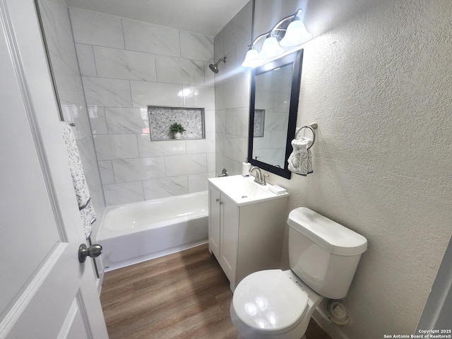 bathroom featuring shower / bathing tub combination, a textured wall, toilet, vanity, and wood finished floors