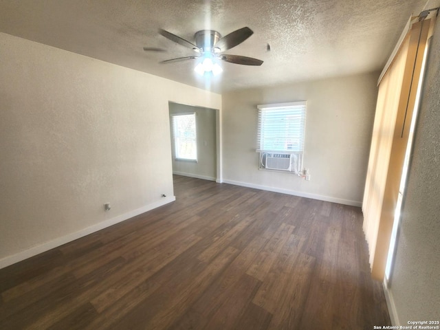 spare room with baseboards, a ceiling fan, dark wood-type flooring, cooling unit, and a textured ceiling