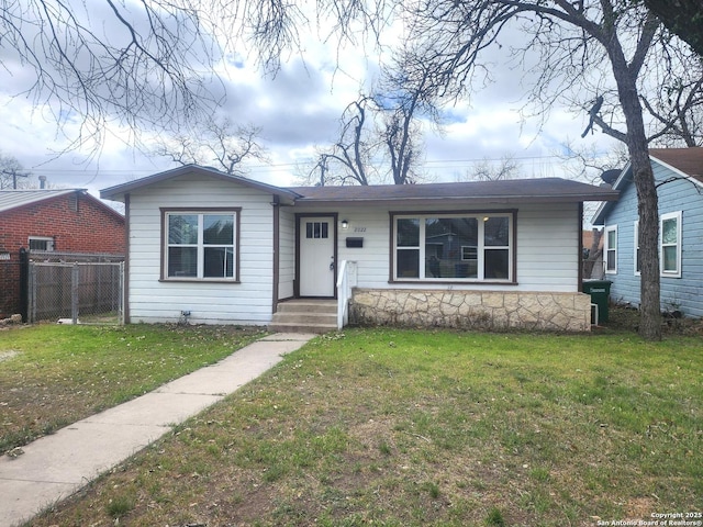 view of front of house with stone siding, a front lawn, and fence