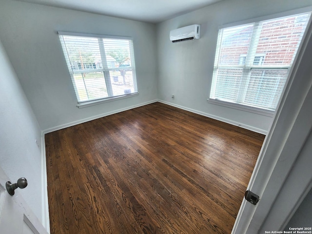 spare room with dark wood-style floors, baseboards, and a wall mounted air conditioner