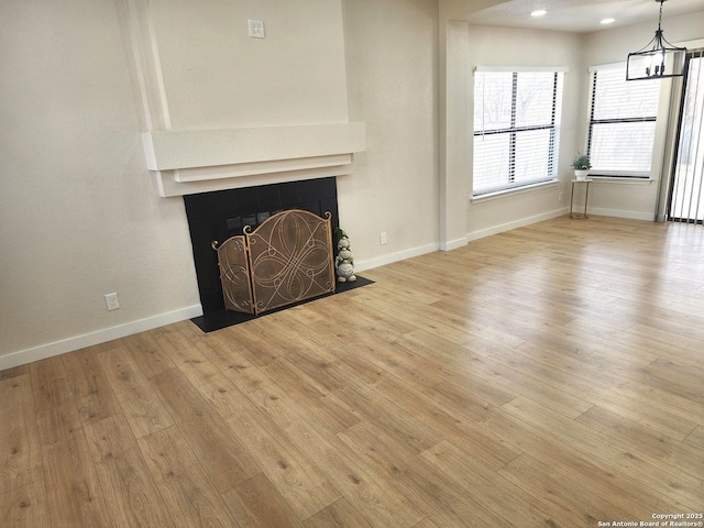 unfurnished living room with baseboards, wood finished floors, and a tile fireplace